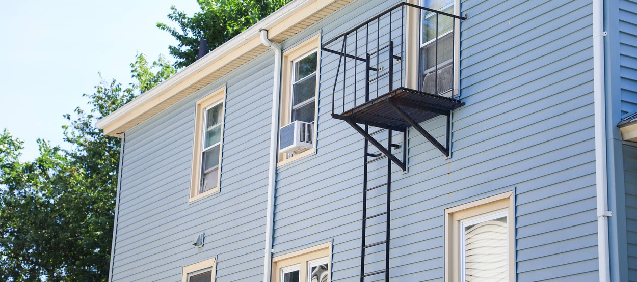 A multi-story building with blue siding and a visible chimney.